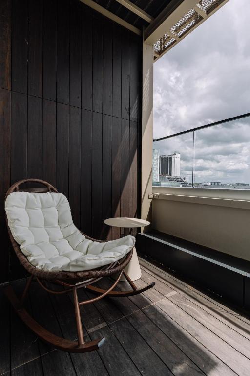 uma cadeira branca num quarto com uma janela em Impiana by Roxy Hotel em Kuching