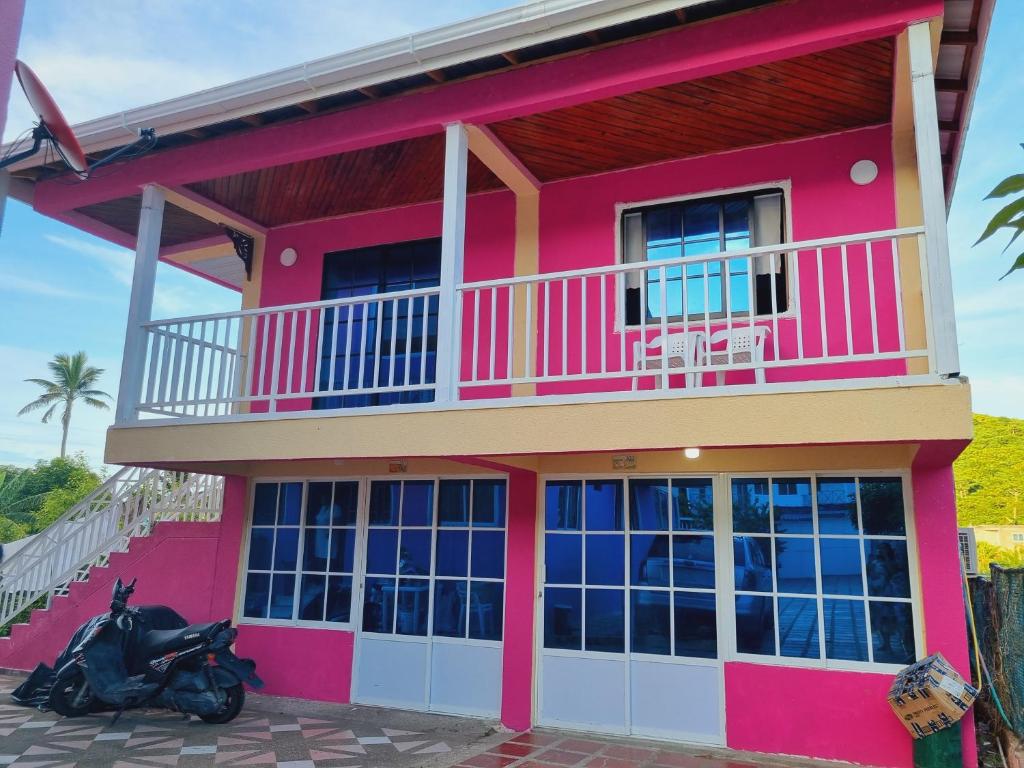 una casa rosa con una moto aparcada delante de ella en Posada Seven Colours Ocean, en Providencia