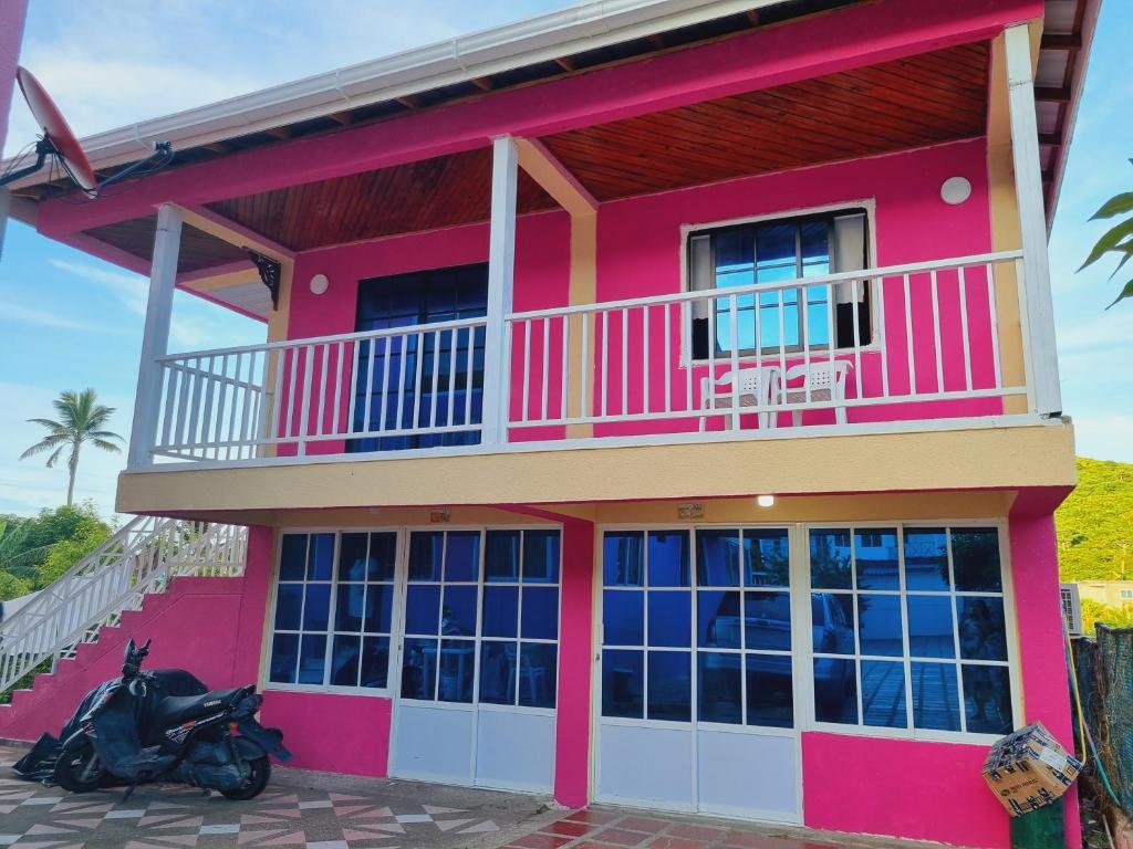 a pink house with a scooter parked in front of it at Posada Seven Colours Ocean in Providencia