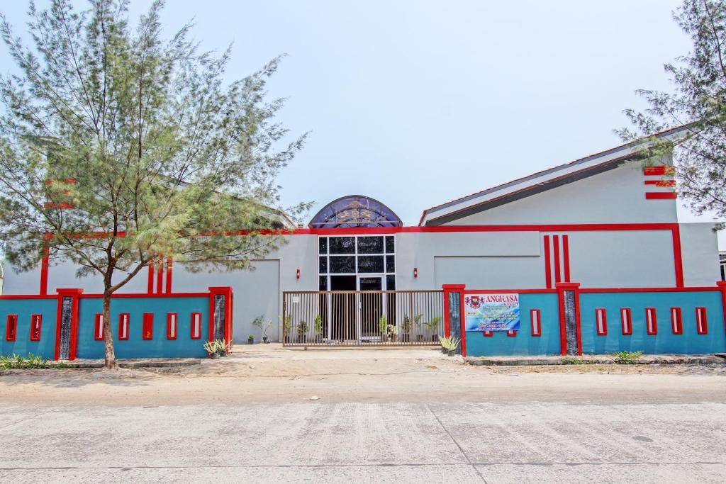ein weißes und rotes Gebäude mit einem Zaun davor in der Unterkunft Capital O 93244 Angkasa Inn in Tegal