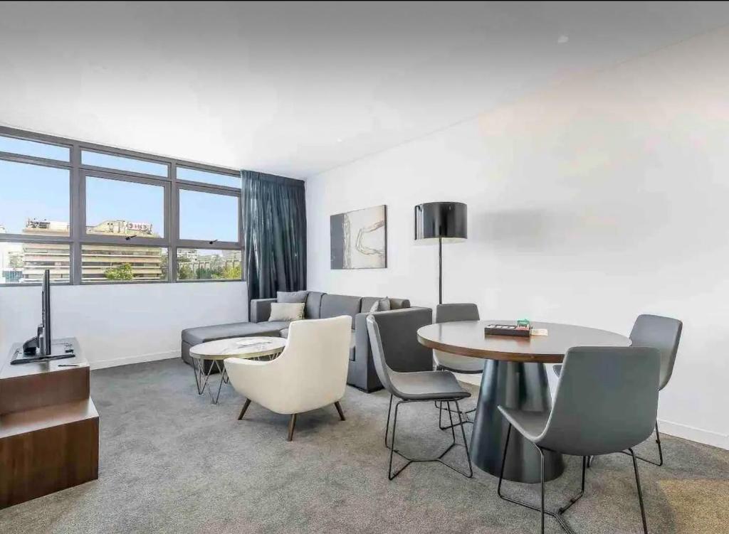 uma sala de estar com um sofá, uma mesa e cadeiras em Premium Apartments Chatswood em Sidney