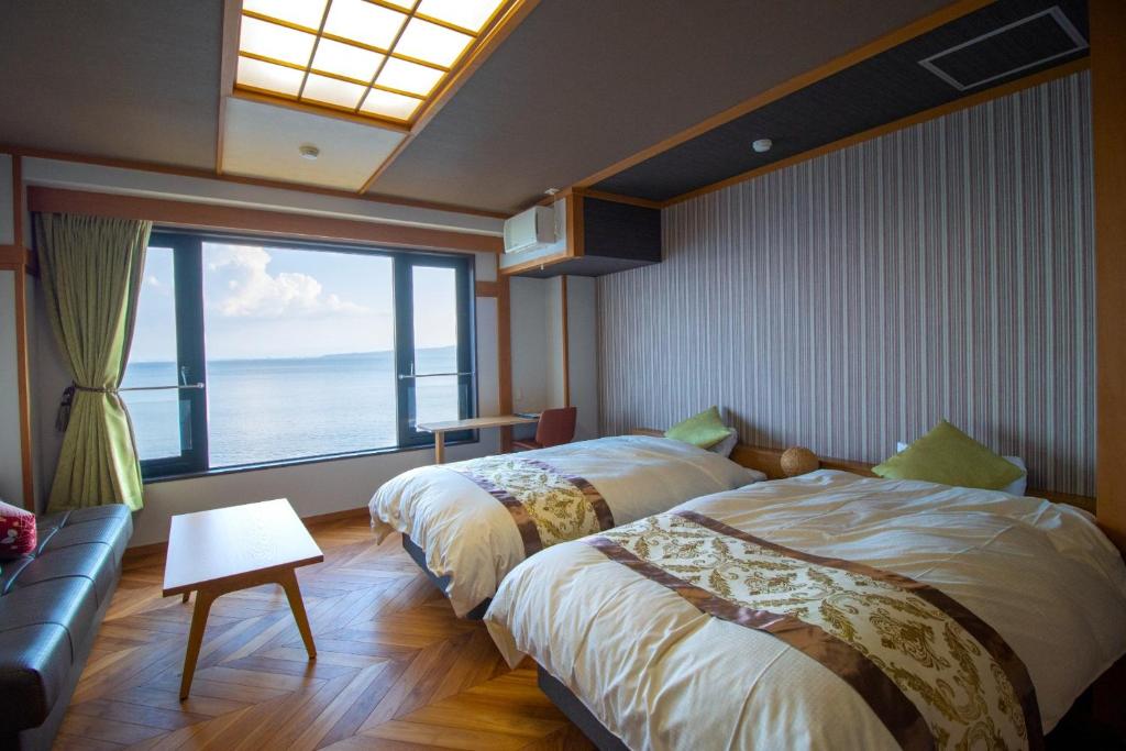 two beds in a room with a large window at La-se-ri Resort & Stay - Vacation STAY 63364v in Himi