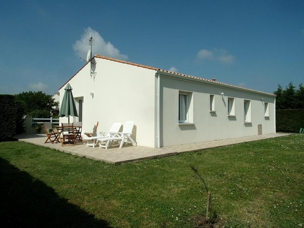 a small white house with chairs and an umbrella at Maison Saujon, 3 pièces, 4 personnes - FR-1-71-76 in Saujon