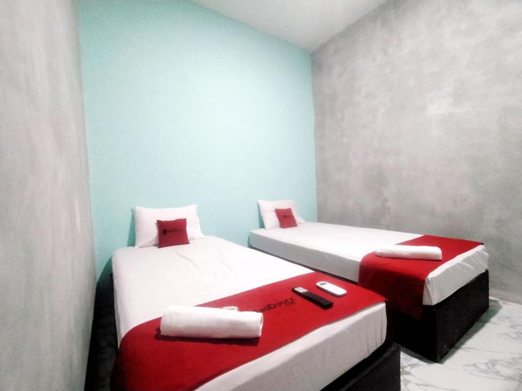 two beds in a room with red and white at RedDoorz Syariah near Exit Tol Bojong Pekalongan in Pekalongan
