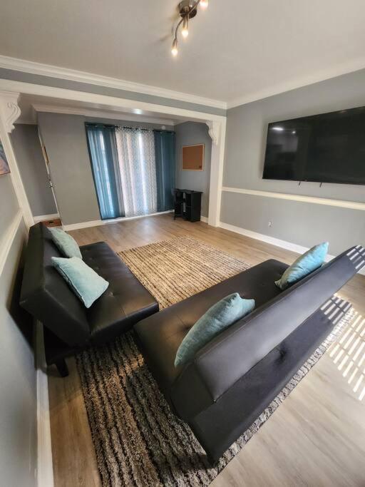 uma sala de estar com um sofá de couro e uma televisão de ecrã plano em Blue Shark *E1* @ Midtown Large 1BR King Suite em Houston