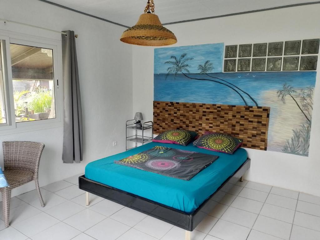 uma cama num quarto com uma pintura na parede em faré apî em Mataiea