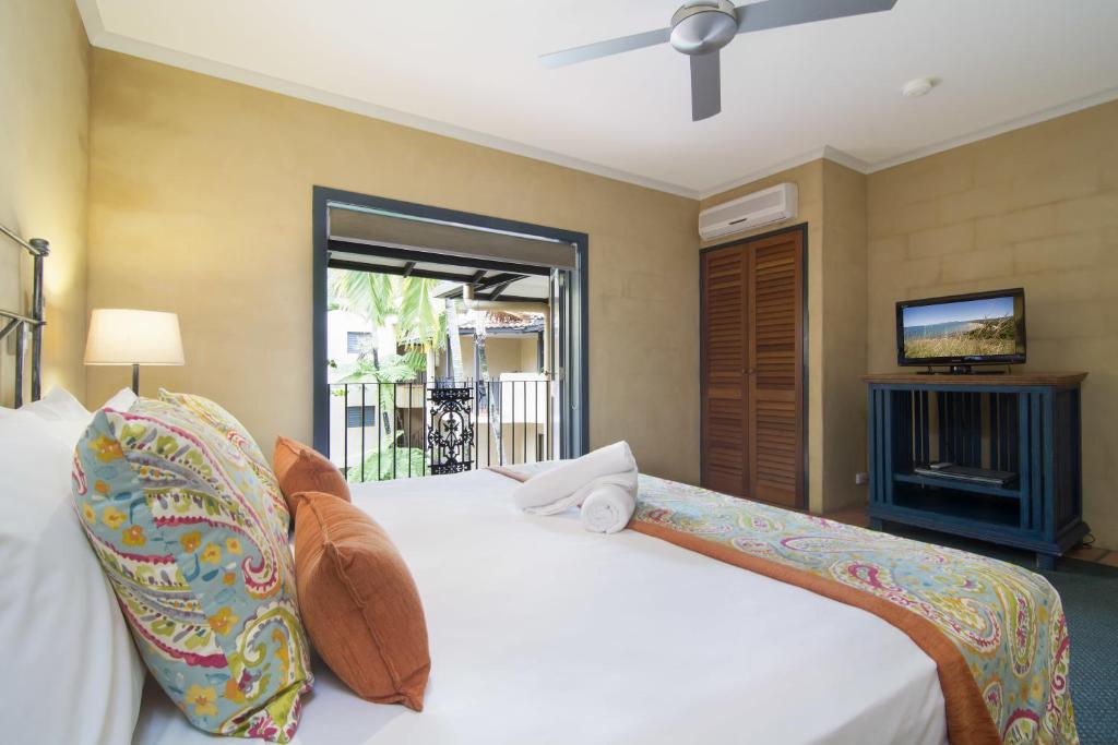 een slaapkamer met een wit bed en een televisie bij Villa San Michele (Official) in Port Douglas