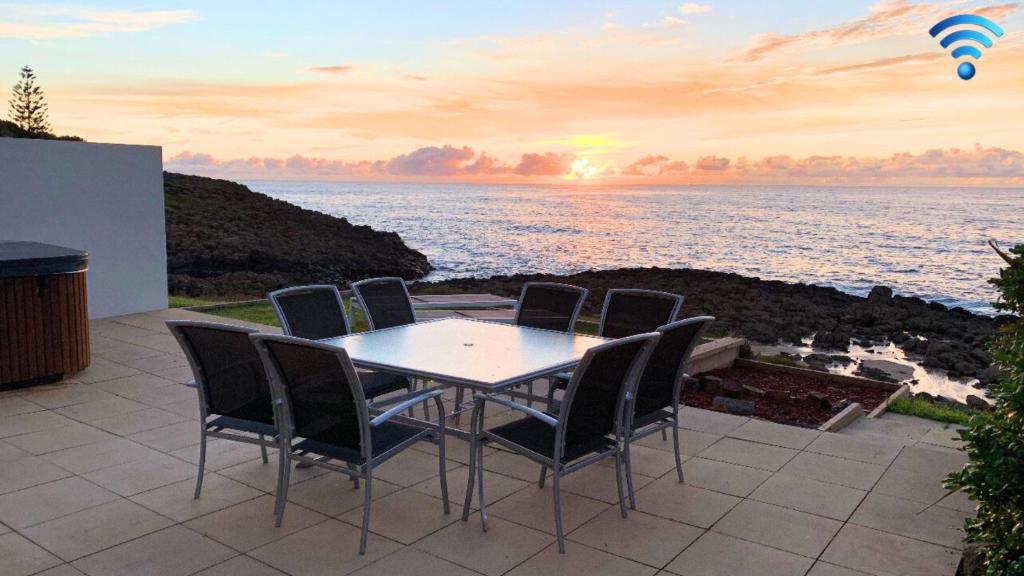 una mesa y sillas en un patio con vistas al océano en Jones Beach House, en Kiama Downs