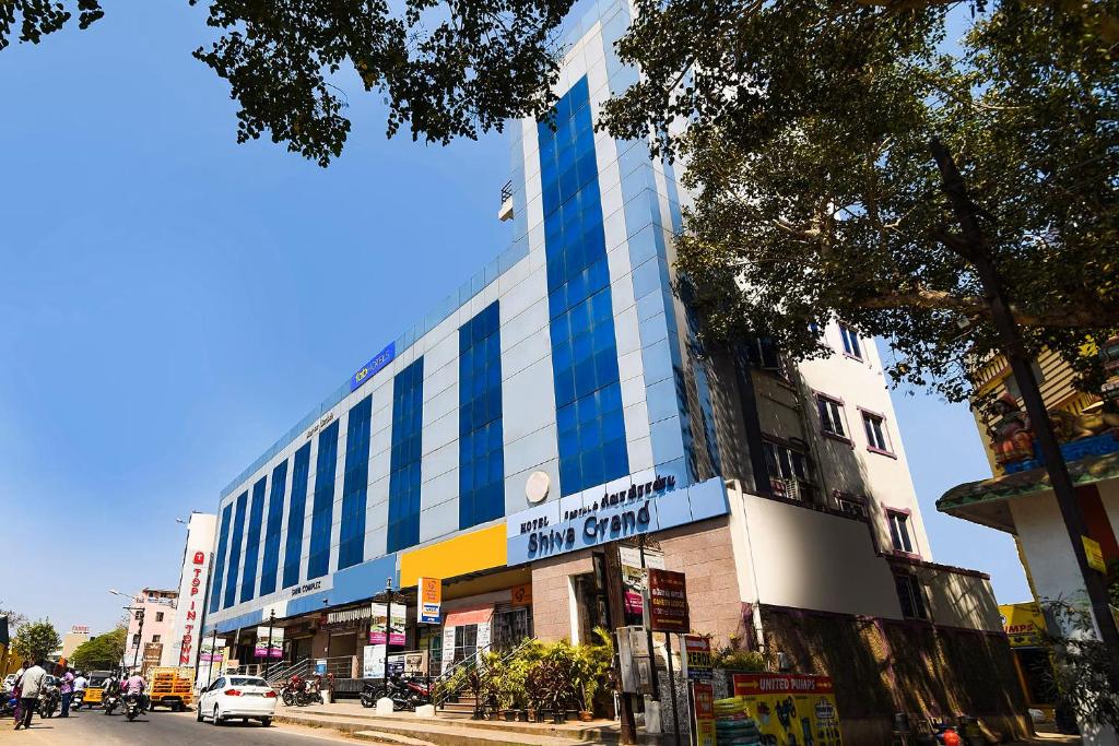 a tall building with blue windows on a city street at FabHotel Shiva Grand in Coimbatore