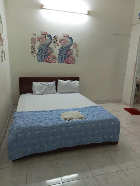 Bett mit blauer Decke in einem Zimmer in der Unterkunft Nhà nghỉ MINH HOÀNG in Vũng Tàu