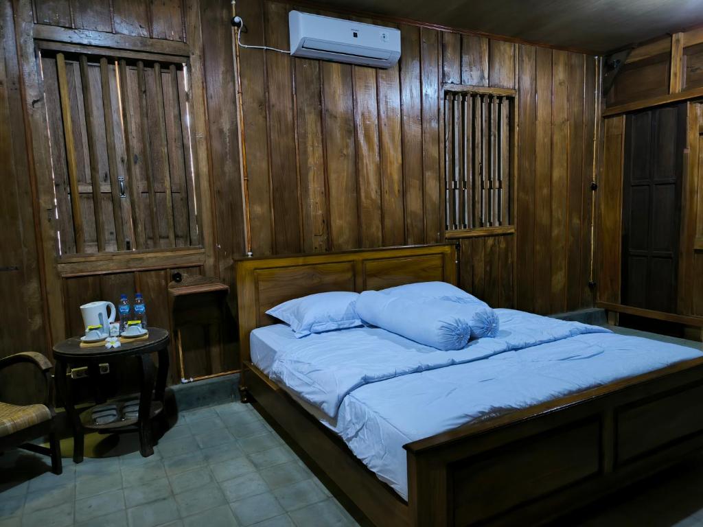 a bedroom with a bed with wooden walls and a table at Puri Swantari Javanese Home Stay in Sleman