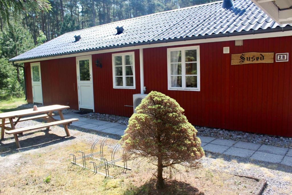 a red cabin with a picnic table and a bench at Charming Cottage Close To The Beach in Vester Sømarken