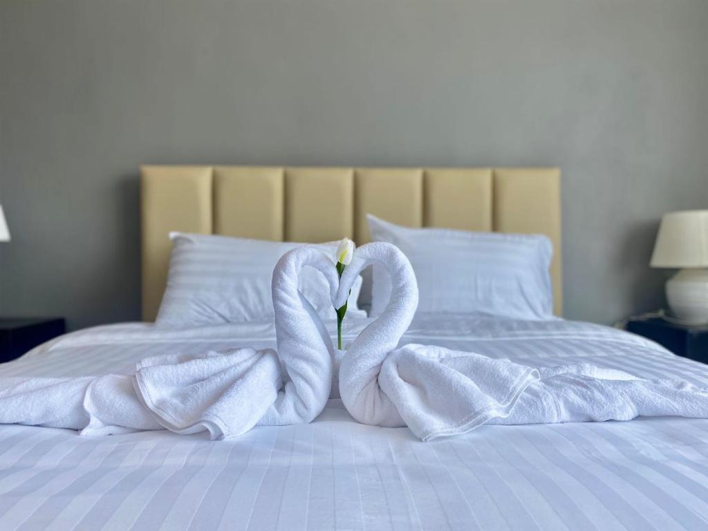 due cigni avvolti in asciugamani seduti su un letto di Tulip Hotel a Louang Namtha