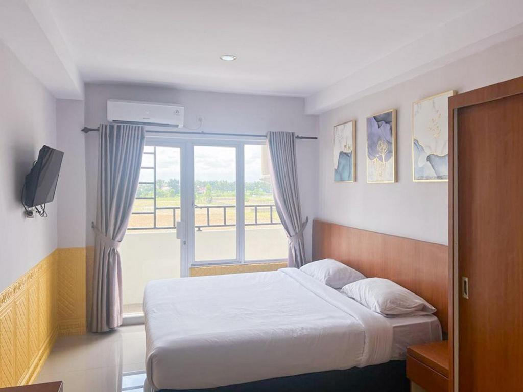 um quarto com uma cama e uma grande janela em Skyview Setiabudi Apartment Medan Redpartner em Sunggal