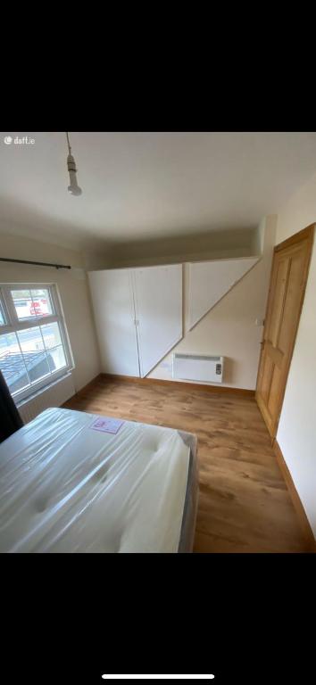 a bedroom with a white bed and a wooden floor at Patrick’s house in Athlone