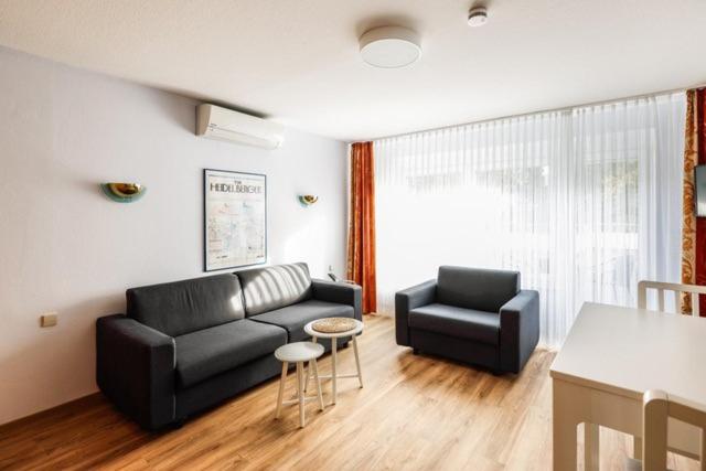 a living room with a black couch and a chair at Hotel ISG Heidelberg in Heidelberg