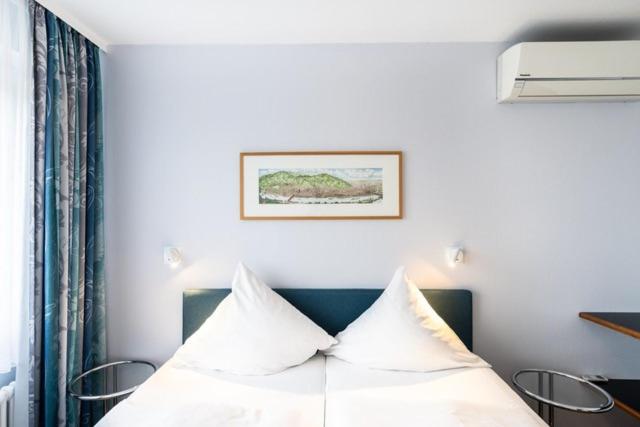 a bedroom with a white bed with two pillows at Hotel ISG Heidelberg in Heidelberg