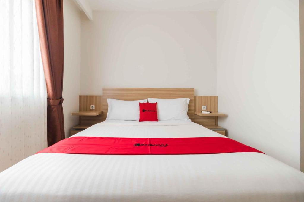 un letto bianco con una coperta rossa sopra di RedDoorz at Homestay Lotus 2 Pangkal Pinang a Pangkal Pinang