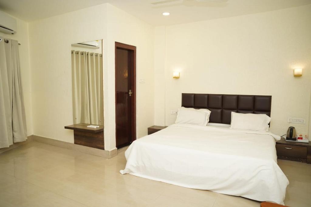 a bedroom with a large white bed and a mirror at VIRAMMA RESORT in Siliguri