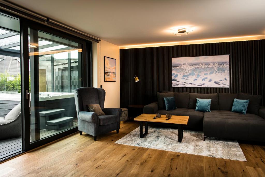 ein Wohnzimmer mit einem Sofa, einem Tisch und einem Stuhl in der Unterkunft Wellness House Energy mit Whirlpool in Timmendorfer Strand