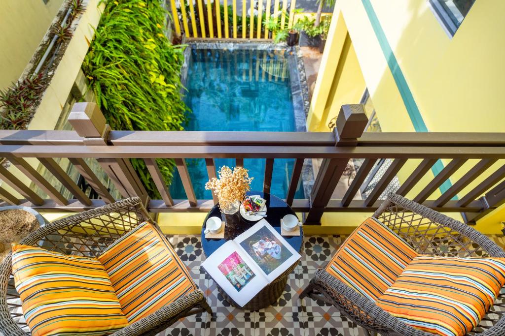 balkon z 2 krzesłami i basenem w obiekcie Villa Soleil Hoi An w Hoi An