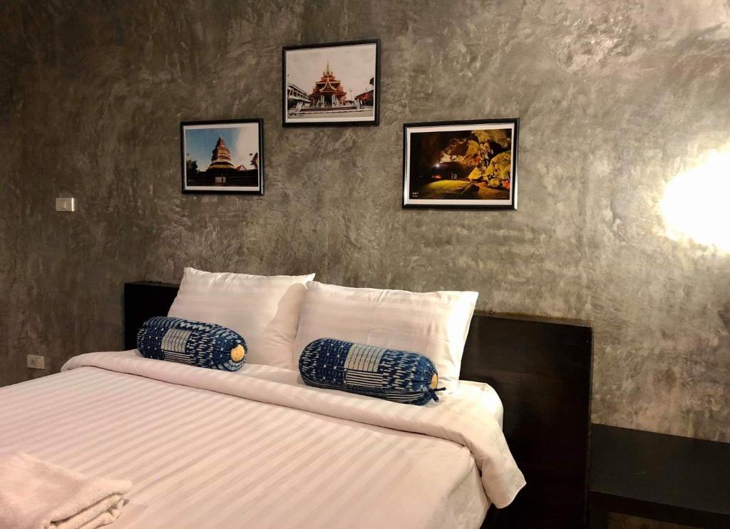 1 dormitorio con 1 cama con 4 cuadros en la pared en Come Moon Loft Hotel, en Phrae