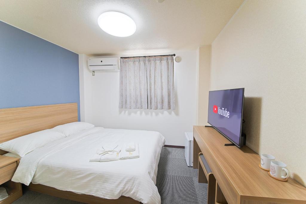 大阪市にあるホテルよしやのベッド1台、薄型テレビが備わるホテルルームです。