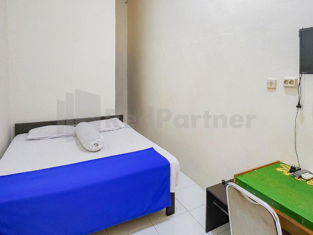 a bedroom with a blue and white bed and a tv at Griya Tambun Raya RedPartner in Tumbangrungan