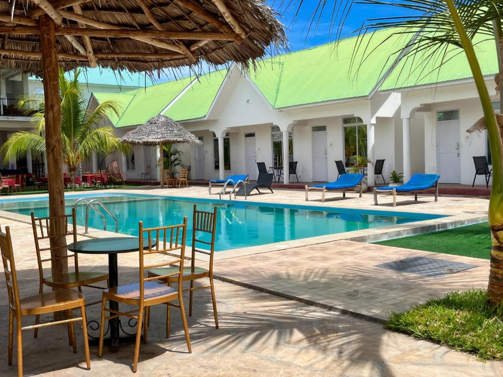 a table and chairs next to a swimming pool at Sunrise Villas in Jambiani