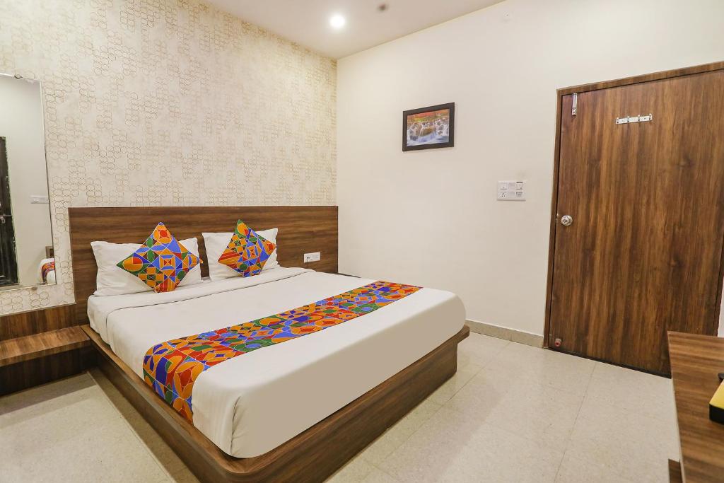 a bedroom with a bed and a wooden door at FabHotel Prince Mama in Gwalior