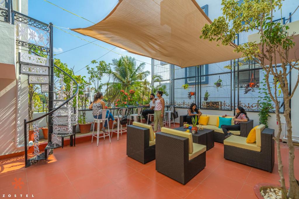 a balcony with people sitting in chairs and tables at Zostel Bangalore (Koramangala) in Bangalore