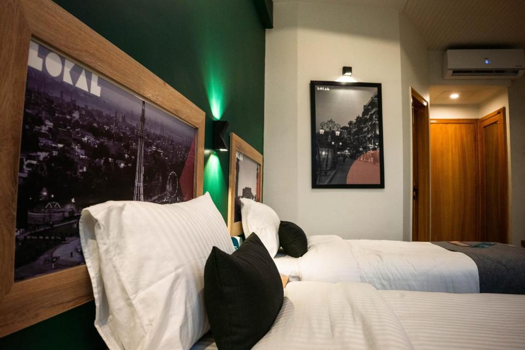 two beds in a hotel room with green lights at LOKAL Rooms x Lahore (Cavalry) in Lahore