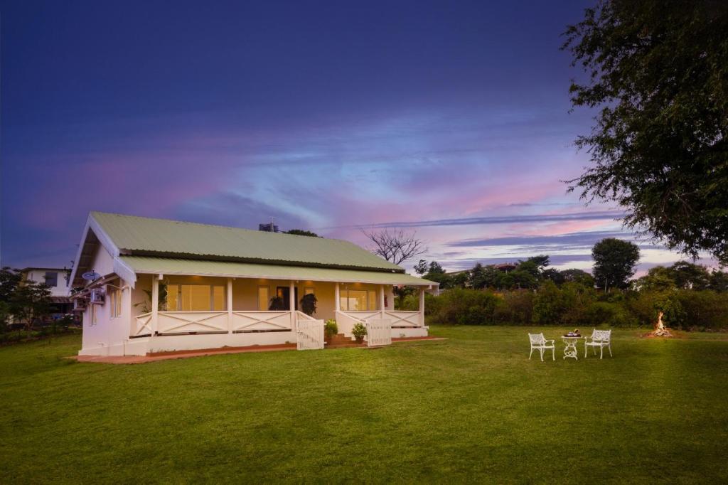 ein weißes Haus mit einem Tisch und Stühlen im Hof in der Unterkunft Wild Pastures by Nature Stays in Masinagudi