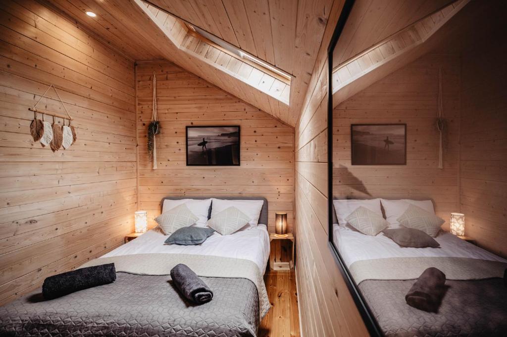 two beds in a room with wooden walls at Dwa Brzegi in Międzywodzie