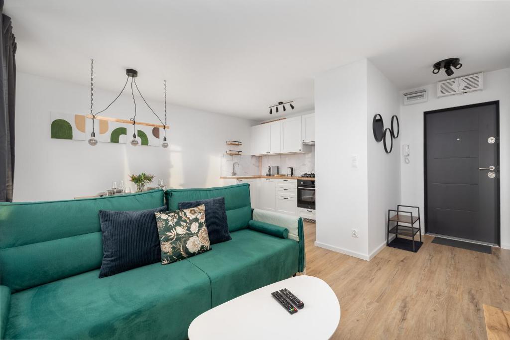 a living room with a green couch and a kitchen at Apartment Near the Warta River by Renters in Poznań