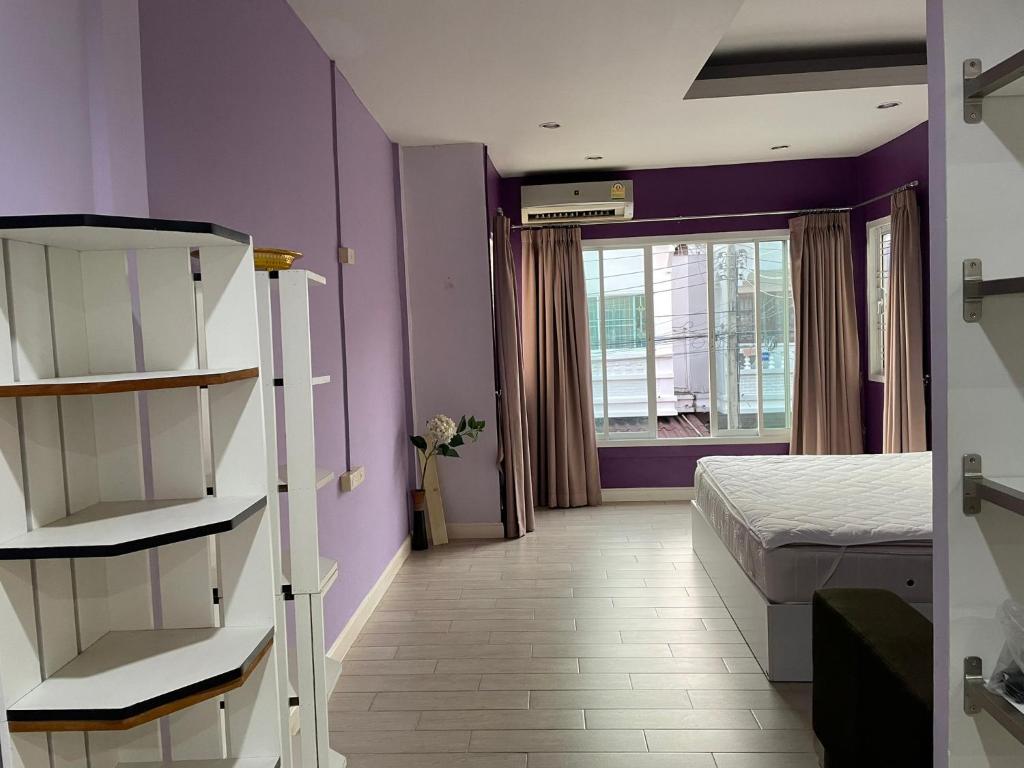 - une chambre avec des murs violets, un lit et une fenêtre dans l'établissement Townhouse 2 Floors @Lertubon Watcharaphon, à Ban Nong Khwang Tawan