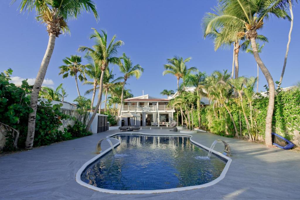 una piscina di fronte a una casa con palme di TRACADERO Beach Club & Holidays Rentals a Bayahibe