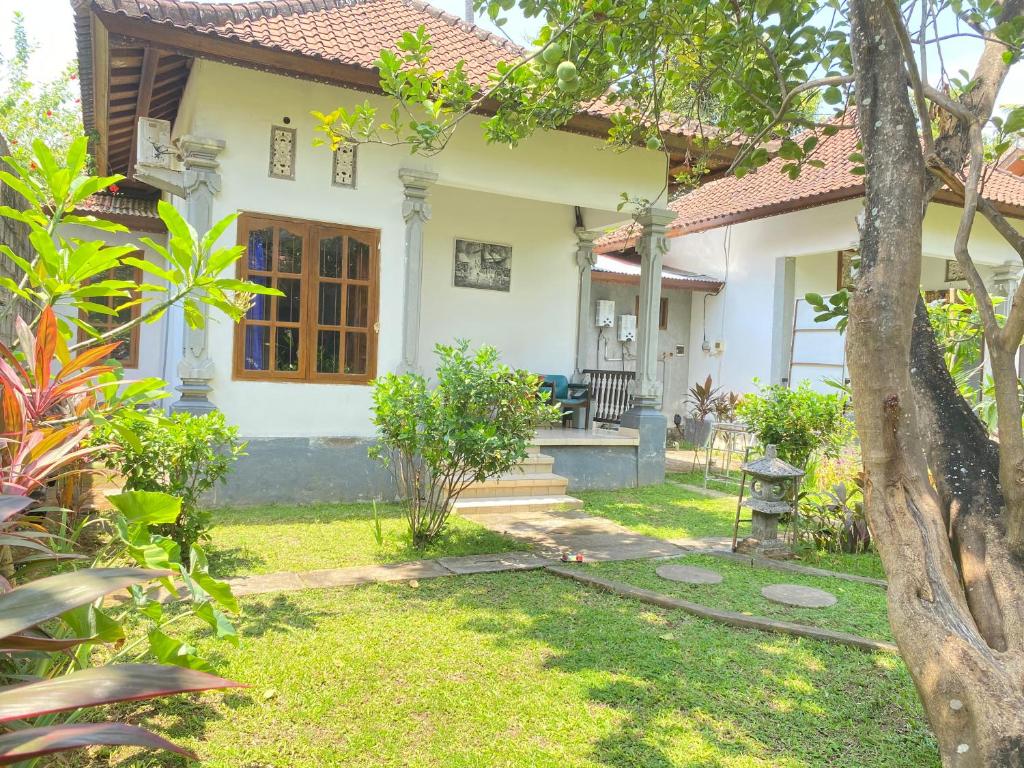 ein weißes Haus mit einem Garten und einem Baum in der Unterkunft Suris bungalows in Buleleng