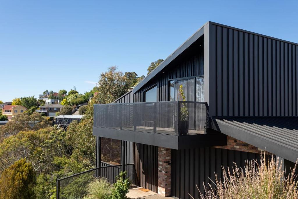a black house on a hill with a balcony at Haven in the Heights - Luxe Design & Sprawling Views in Inveresk