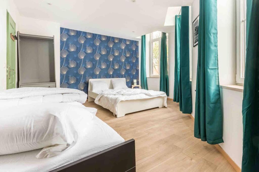 a bedroom with two beds and a blue wall at Maison spacieuse proche Lille in Roubaix