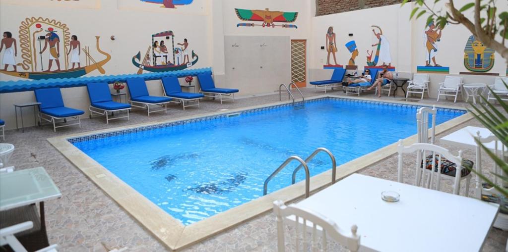 una piscina en una habitación con sillas y mesa en Amon Hotel, en Luxor