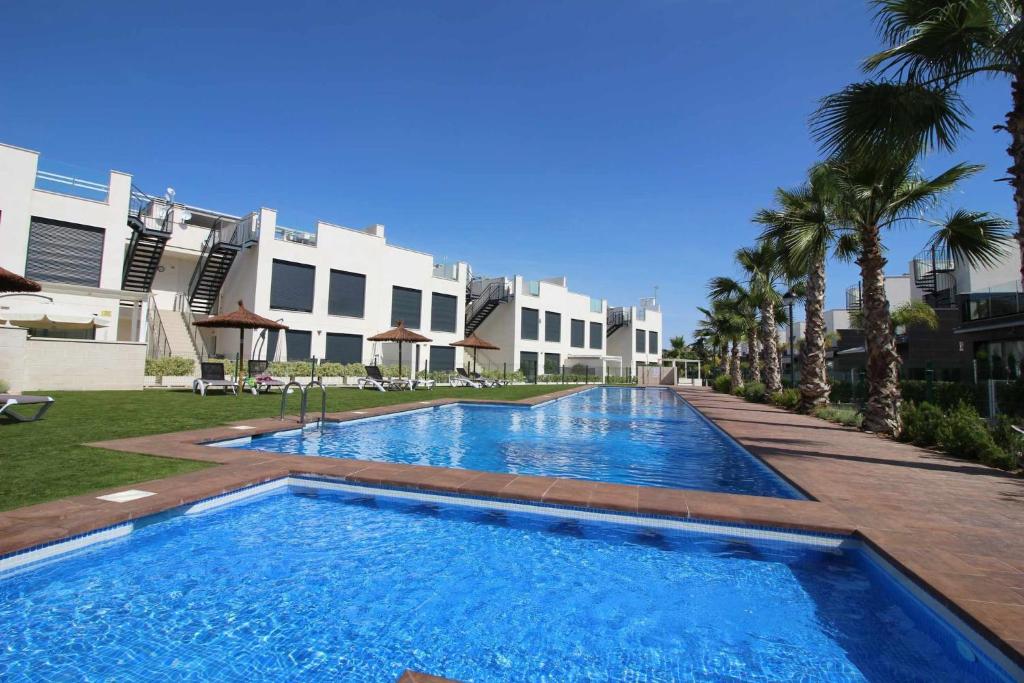 a swimming pool in front of a building with palm trees at Villa Tindra in Torrevieja
