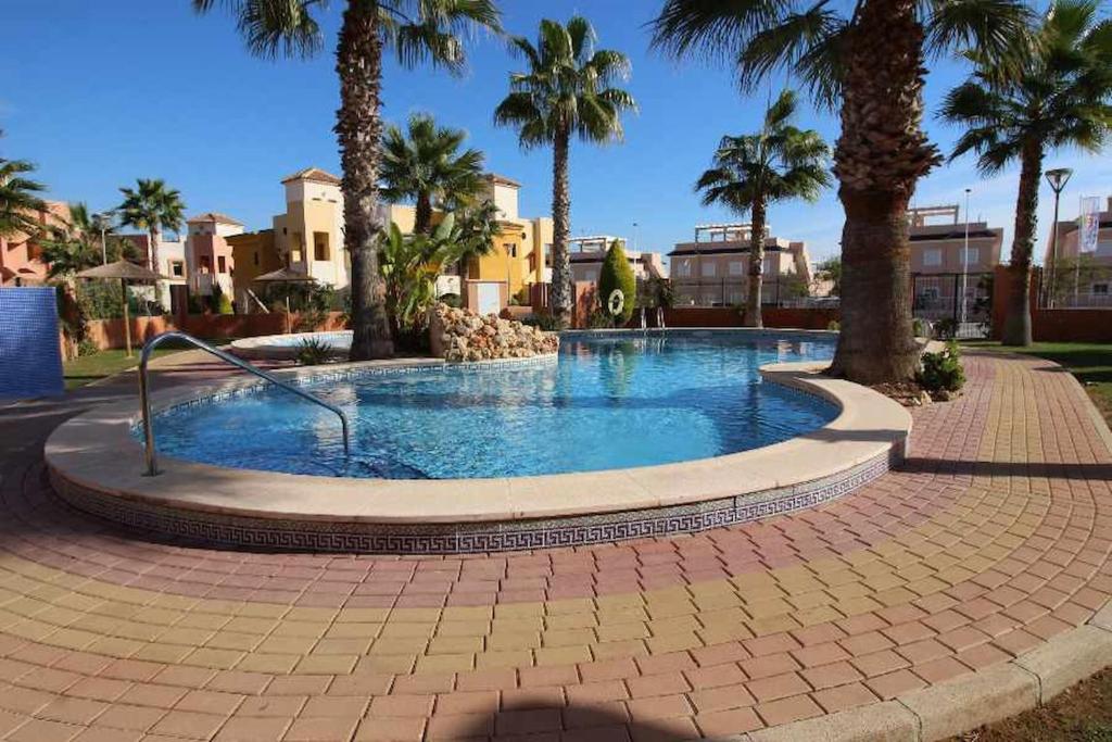 a large swimming pool with palm trees and buildings at Punta Marina Green Paradise in Torrevieja