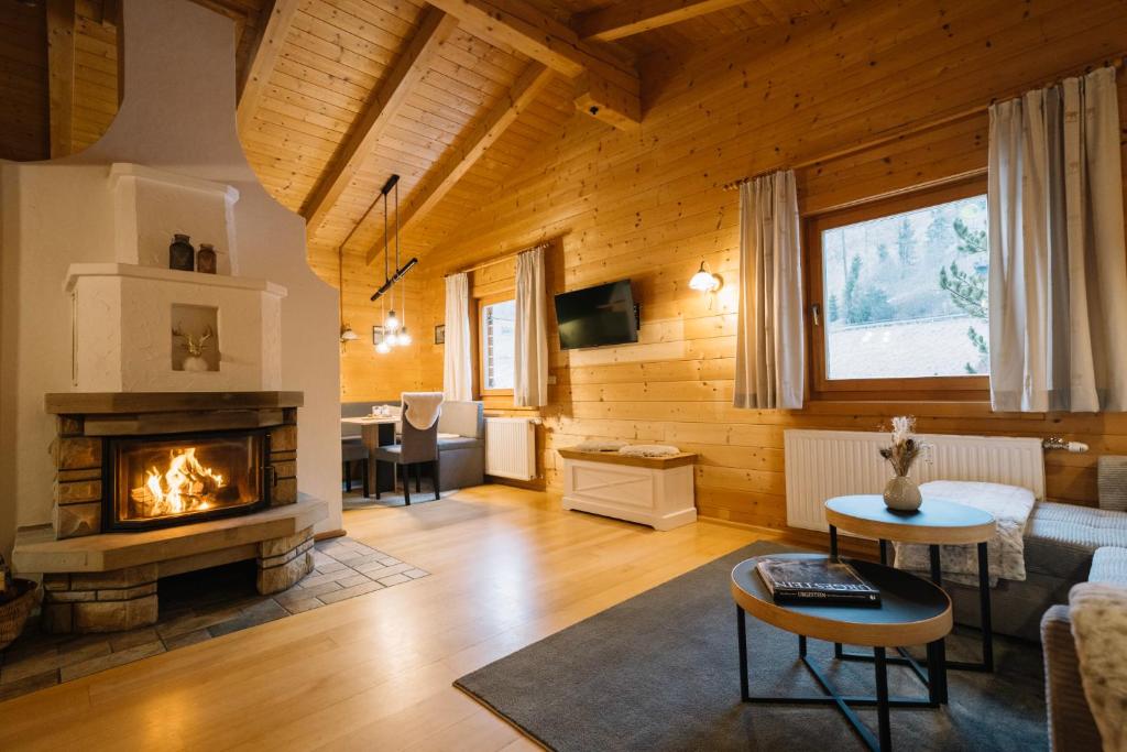 a living room with a fireplace in a wooden house at Steinnock Chalet in Bad Kleinkirchheim