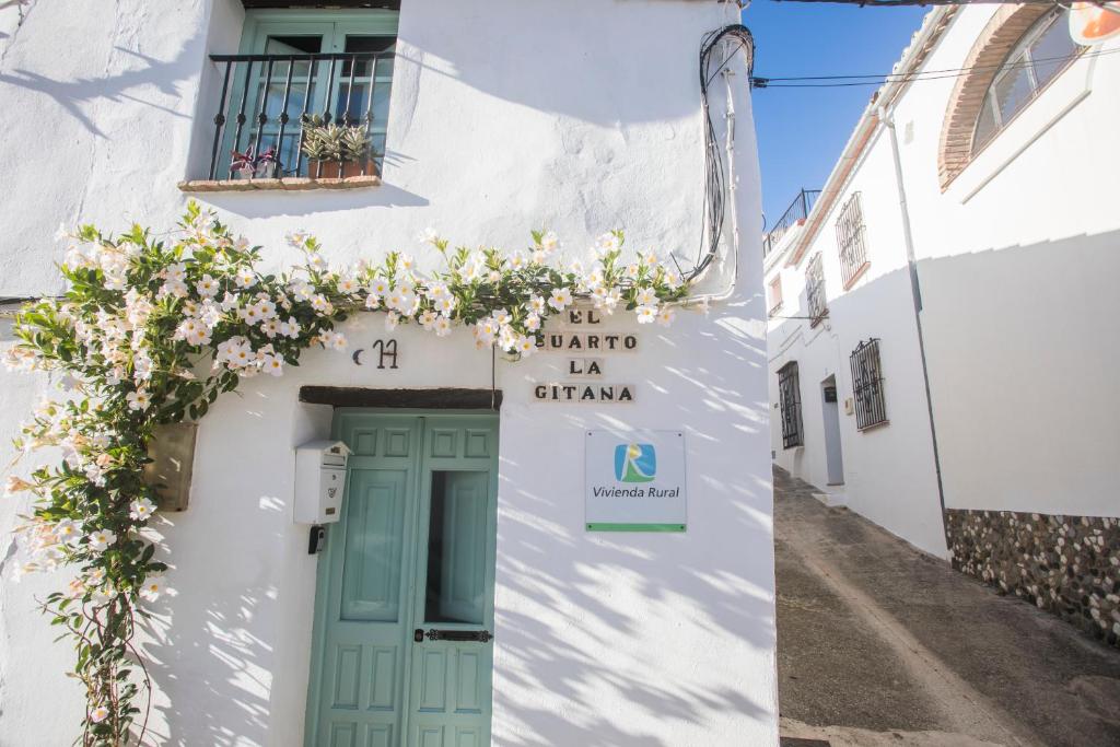 ein weißes Gebäude mit grüner Tür und Blumen in der Unterkunft EL CUARTO LA GITANA in Jimena de la Frontera