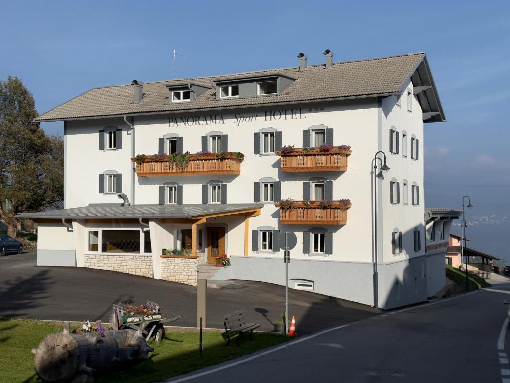 a large white building with balconies on a street at PANORAMA SportHOTEL in Folgaria