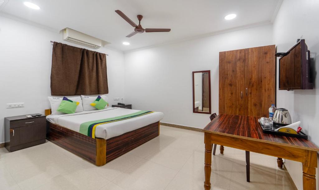 1 dormitorio con cama y escritorio de madera en Treebo Trend NGH Transit, en Chennai