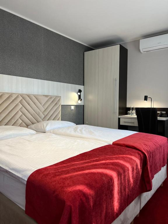 a bedroom with a large bed with a red blanket at Hotel Olimp in Prudnik