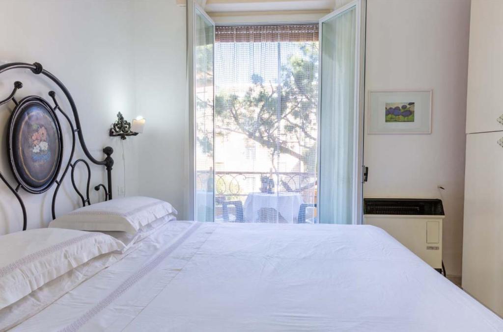 - une chambre avec un lit blanc et une grande fenêtre dans l'établissement Bilocale Imperatrice, à Sanremo