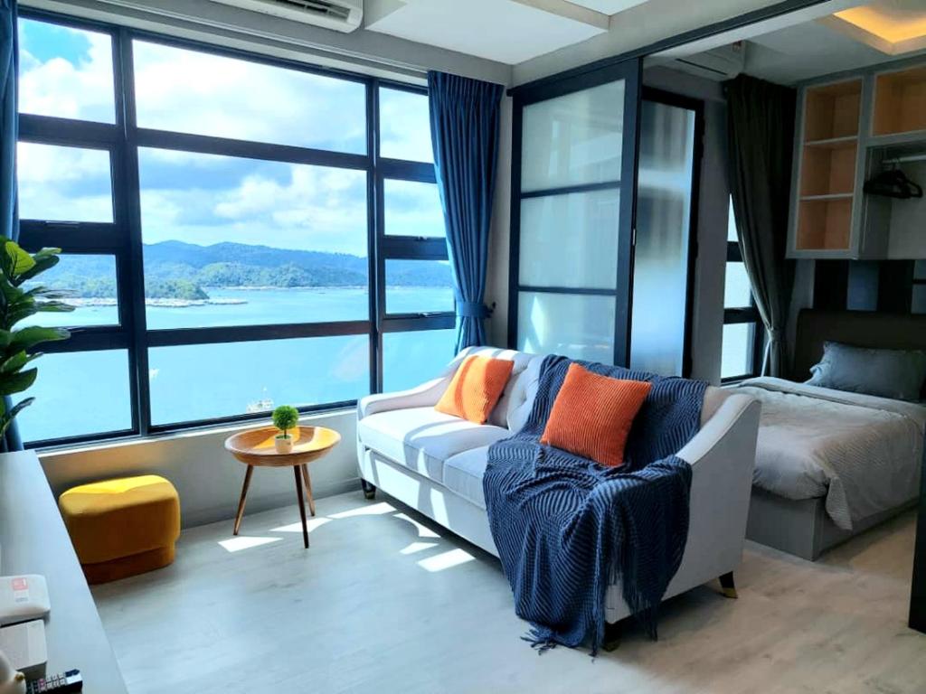 a living room with a couch and a bed and large windows at J'Stay Seaview Suite Jesselton Quay Kota Kinabalu in Kota Kinabalu